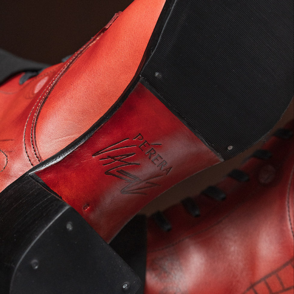 Close-up of red leather shoes with black soles on a dark background